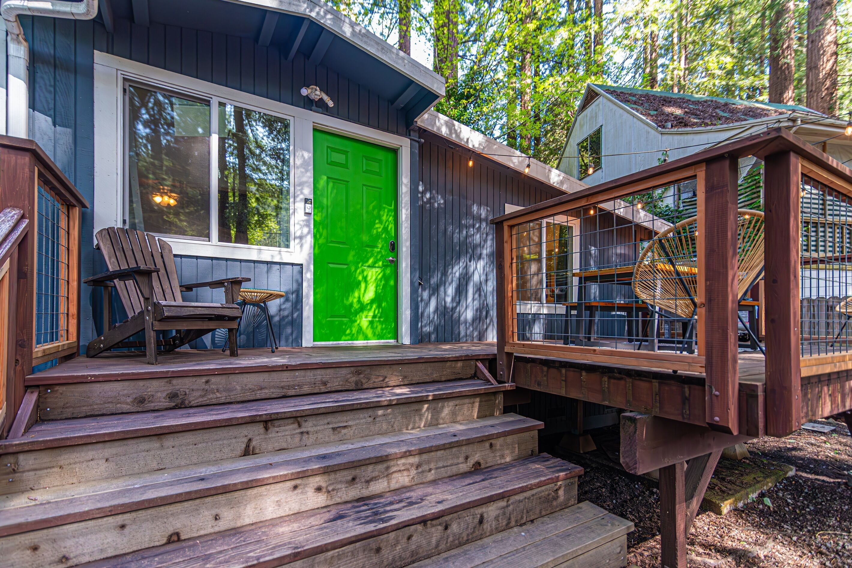 Un patio in legno con una scalinata che conduce a una casa con una porta verde.