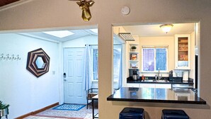 Une cuisine moderne avec un îlot central, deux tabourets de bar et une tête de cerf décorative fixée au plafond.