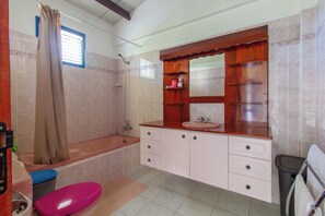 Un baño con bañera, lavamanos y tocador con cajones.