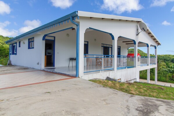 Un edificio blanco con detalles azules y un porche cubierto.