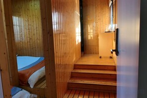 Un interior de madera con una cama, una escalera de madera y una puerta.