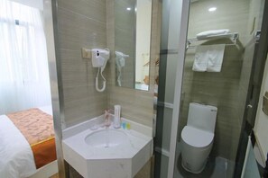 A hotel bathroom with a glass-enclosed shower, a sink with toiletries, and a toilet. - Shanghai Yajing Business Hotel (Xinhua Hospital Branch) (Shanghai)