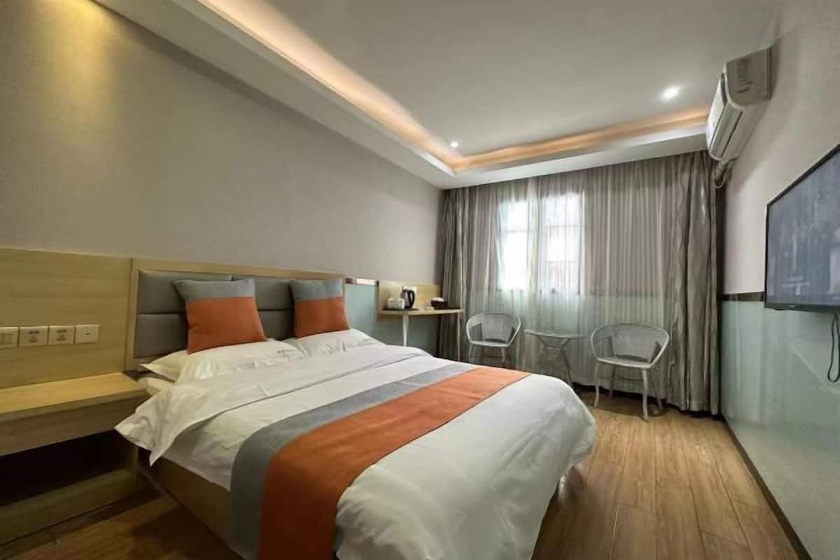 Une chambre d’hôtel équipée d’un lit, d’un bureau, de deux chaises, d’une télévision et d’un appareil de climatisation.