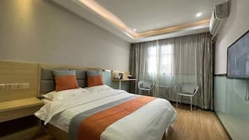 Habitación de hotel con cama, escritorio, dos sillas, televisión y aire acondicionado.