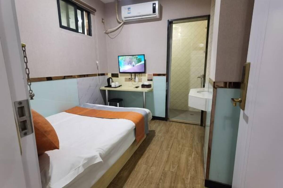 Une chambre d’hôtel équipée d’un lit, d’un bureau avec un ordinateur, d’un lavabo et d’un appareil de climatisation.