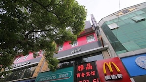 A commercial area with various storefronts including a McDonald's, Watsons pharmacy, and a building with a sign that reads "McCafe." - Shanghai Yajing Business Hotel (Xinhua Hospital Branch) (Shanghai)