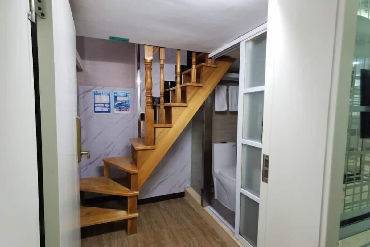 Un escalier en bois mène à une salle de bain dotée d’une cabine de douche en verre.