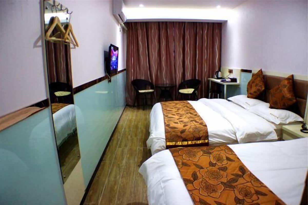 Une chambre d’hôtel avec deux lits, un bureau, une chaise, une télévision et un miroir.