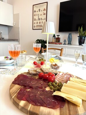 Ein Tisch mit einer Wurstplatte, Weingläsern mit Rosé und einer Lampe.