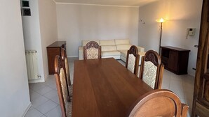 Un área de comedor con una mesa y sillas de madera, un sofá, una lámpara y un armario.