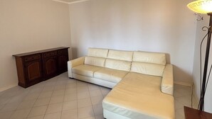 Una habitación con un amplio sofá en forma de L, un aparador de madera y una lámpara de pie.