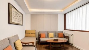 A living room with a sofa, a small table, and a radiator. - Beijing Spring Hotel (Beijing)