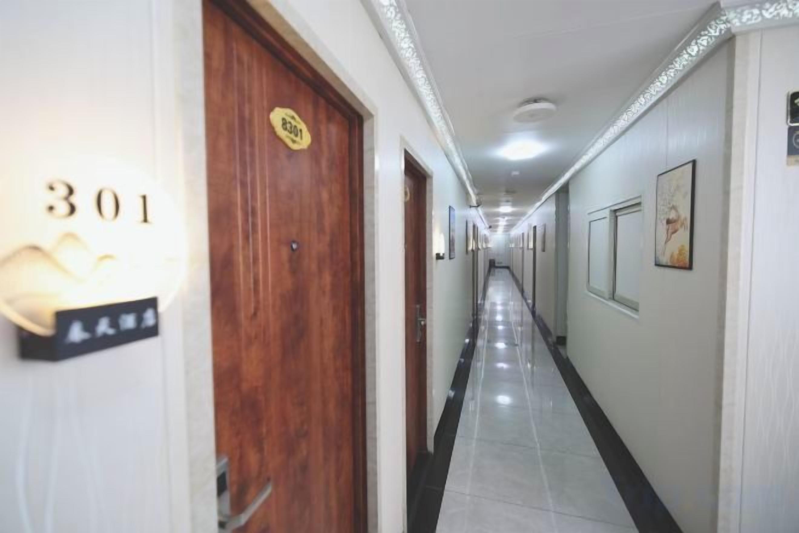 A hotel corridor with doors numbered 301 and 302, a tiled floor, and framed pictures on the walls.