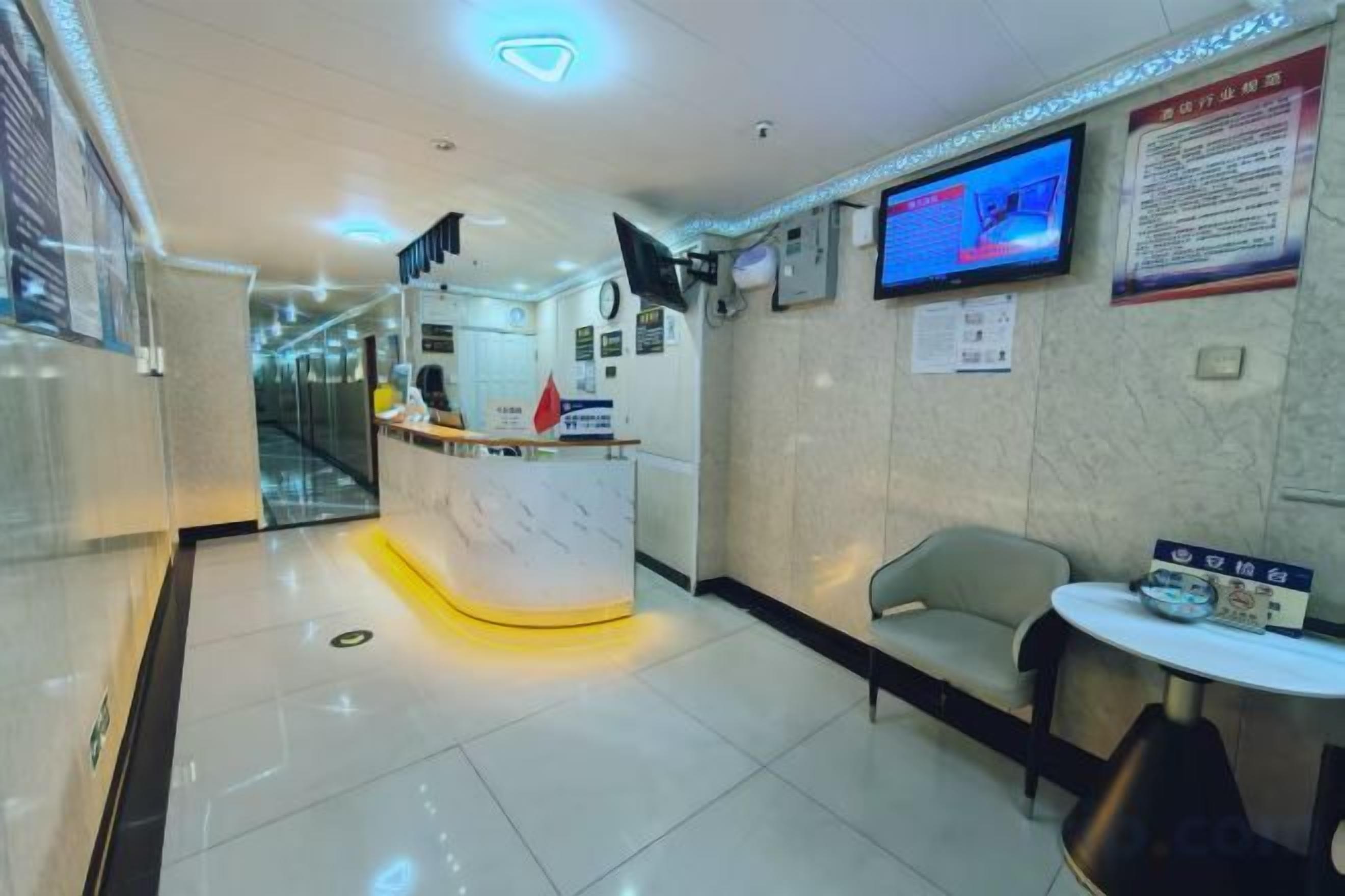 A hotel reception area with a reception desk, a seating area, and a television screen.