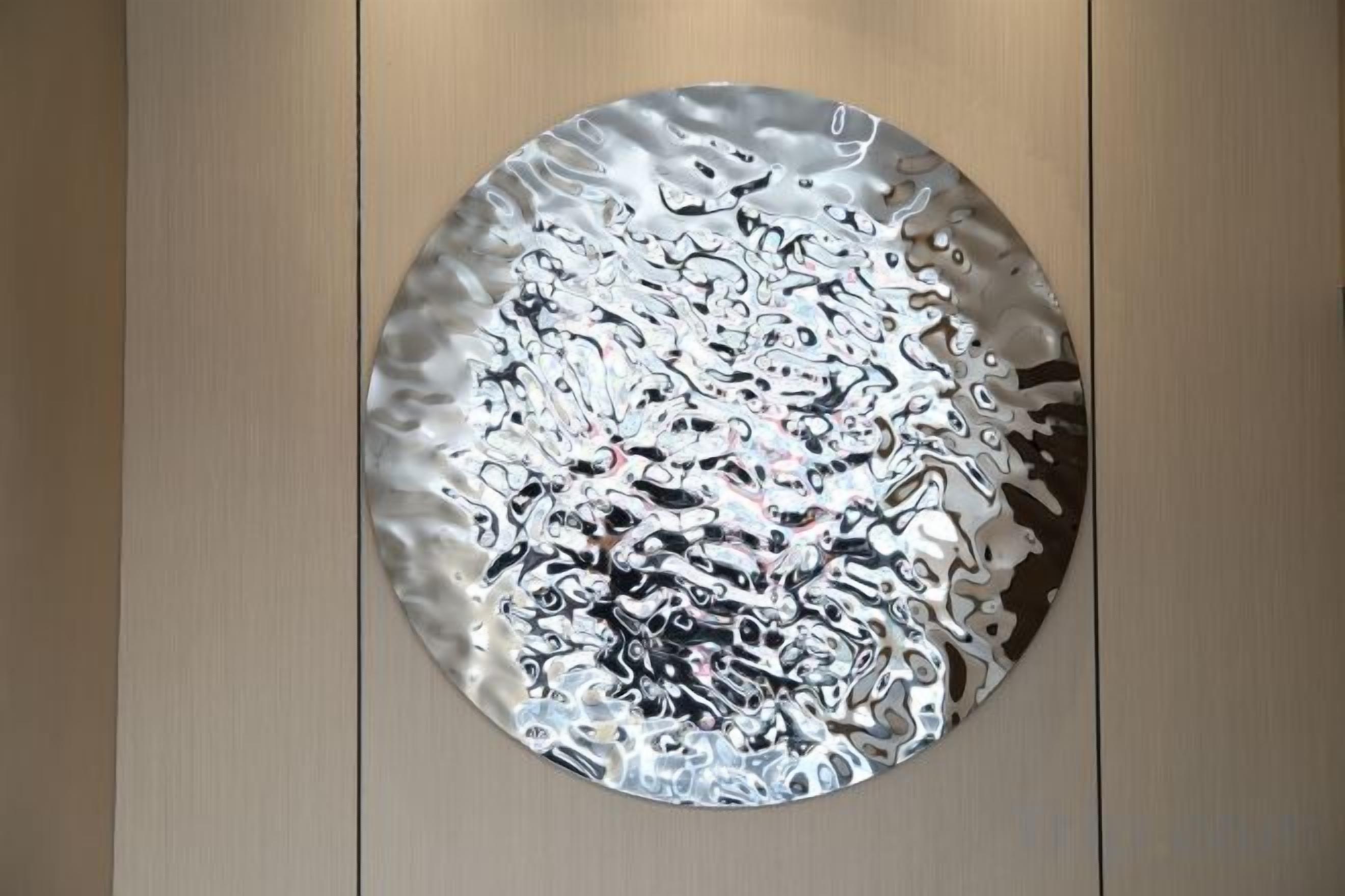 A circular metallic object with a textured surface, mounted on a wall.