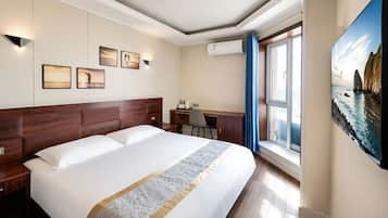 Una habitación de hotel con una cama grande, un escritorio y un cuadro en la pared.