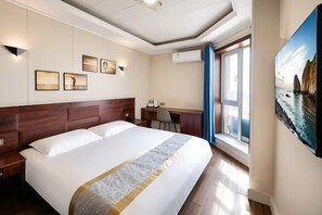Habitació d'hotel amb un llit gran, un escriptori i un quadre a la paret.