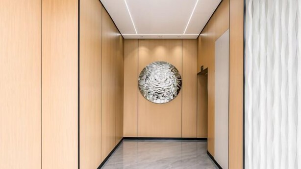A hallway with wooden paneling, a circular wall art piece, and a marble floor. - Beijing Spring Hotel (Beijing)