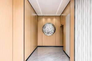A hallway with wooden paneling, a circular wall art piece, and a marble floor. - Beijing Spring Hotel (Beijing)