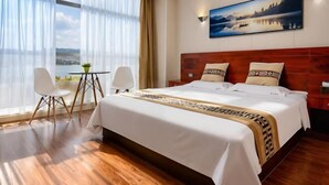 A hotel room with a large bed, two chairs, a small table, and a painting on the wall. - Beijing Spring Hotel (Beijing)