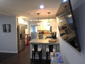 Enjoy cooking in this well-equipped kitchen with a sleek island, bar stools, and ample counter space.
