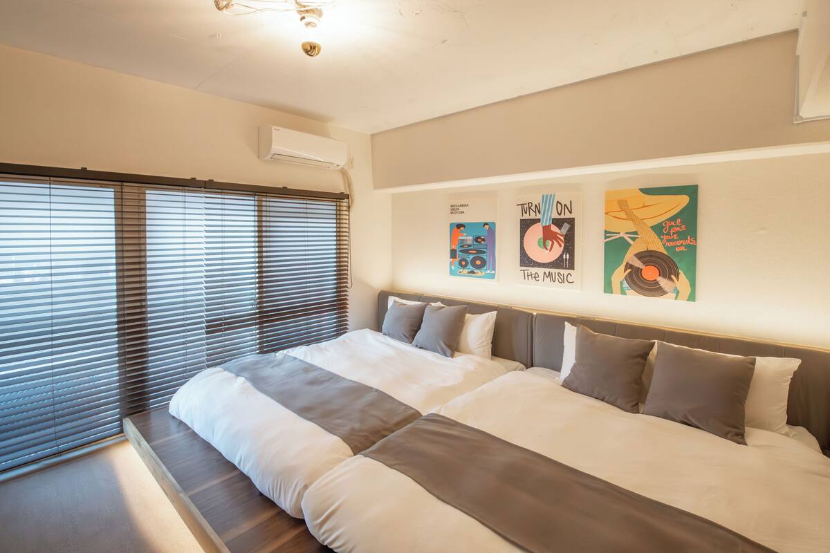 Une chambre à coucher moderne avec un grand lit, un banc intégré et trois œuvres d’art accrochées au mur.