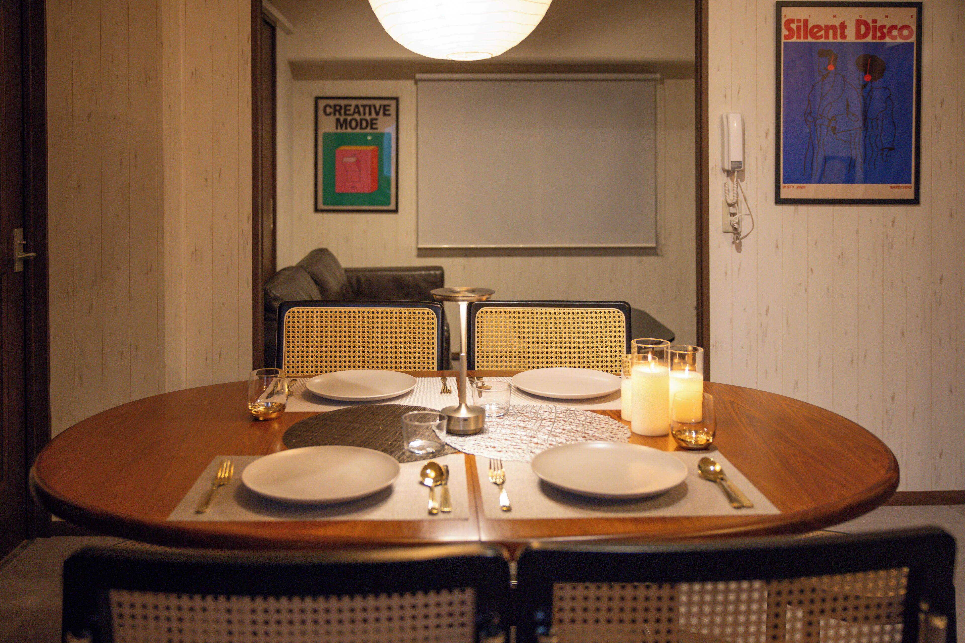 A dining table set for four with a candle, a glass, and cutlery.