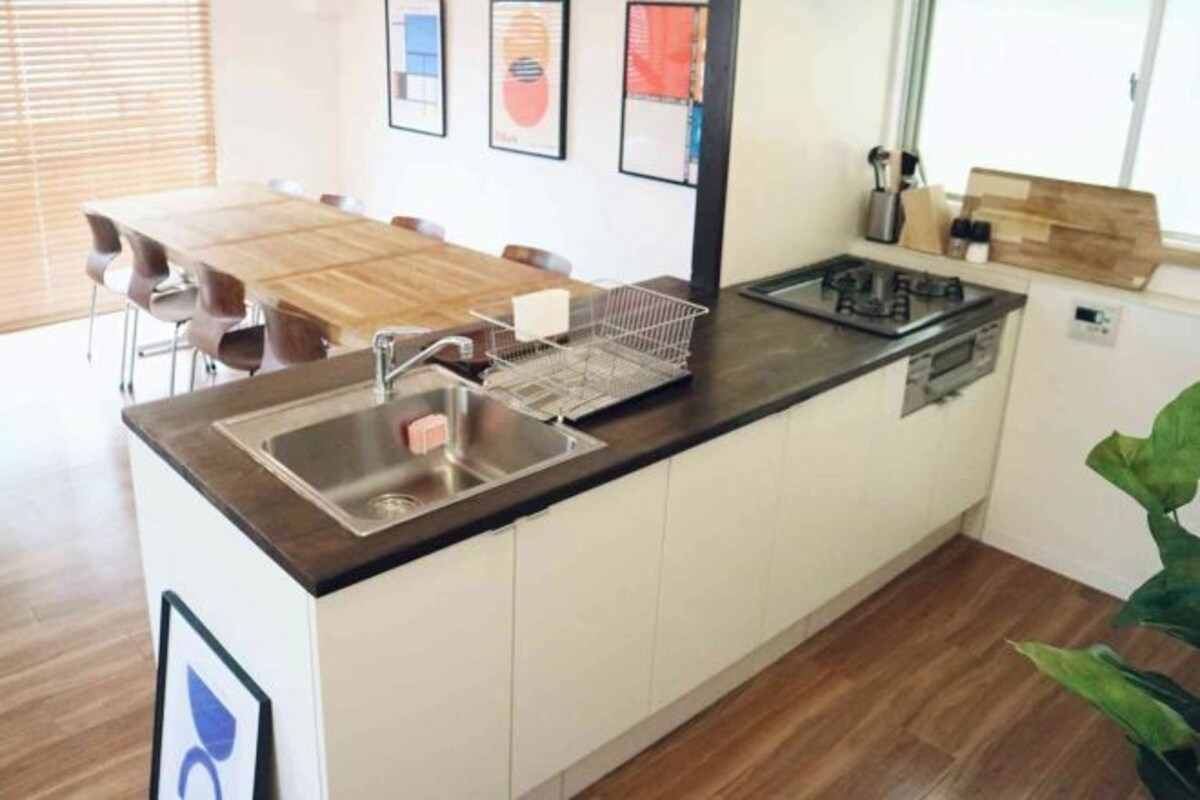 Een moderne keuken met een houten eettafel, een inbouwspoelbak en roestvrijstalen apparatuur.