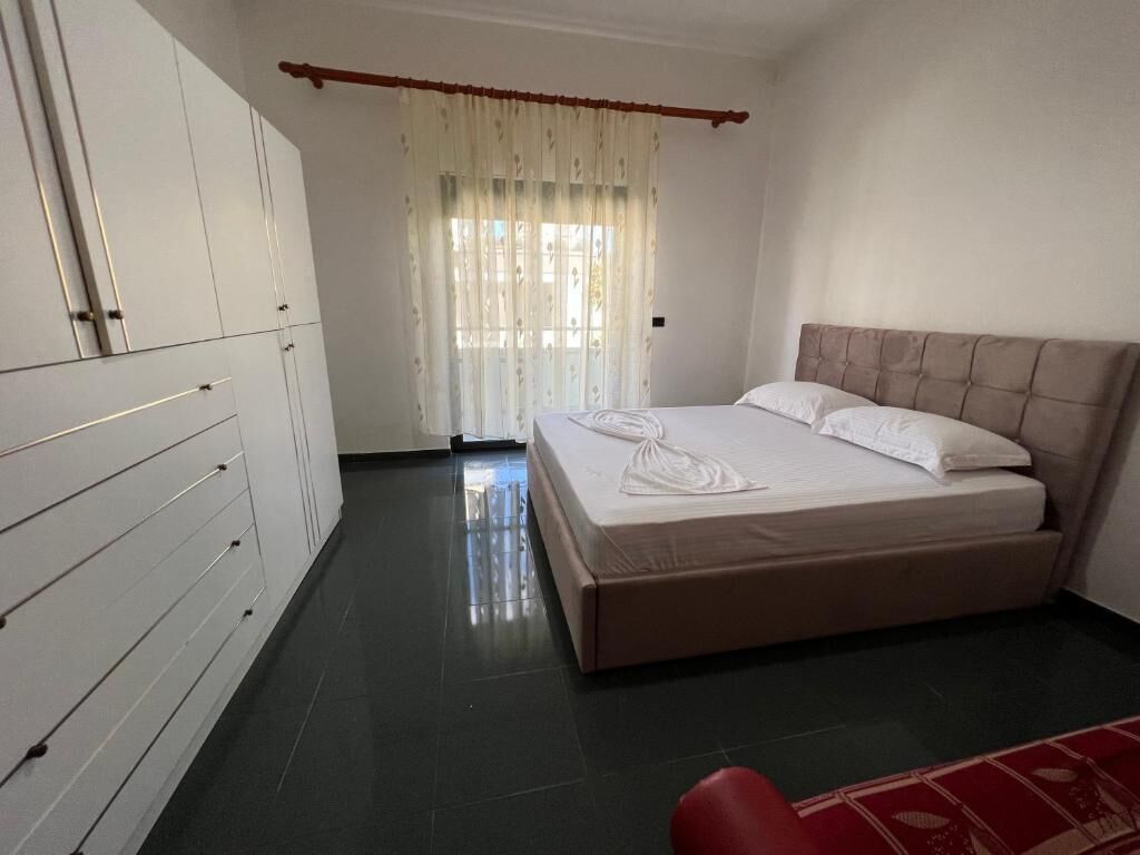 Un dormitorio con una cama, un armario y una ventana con cortinas.