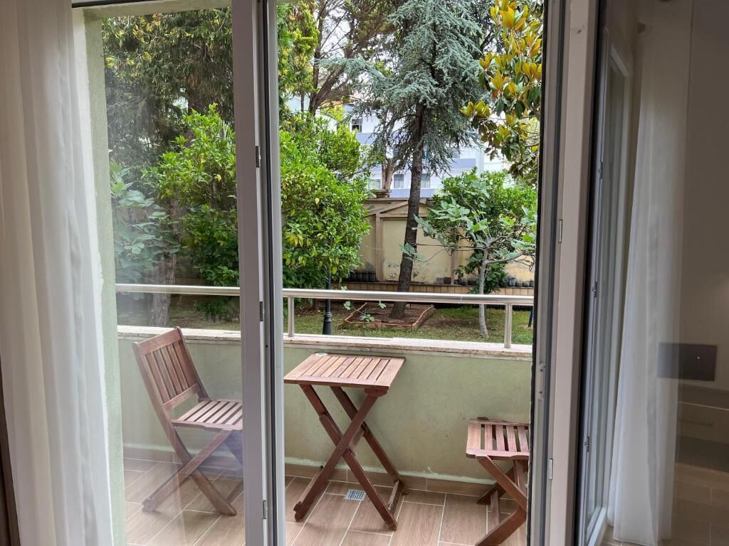 A balcony with two wooden chairs and a small table.
