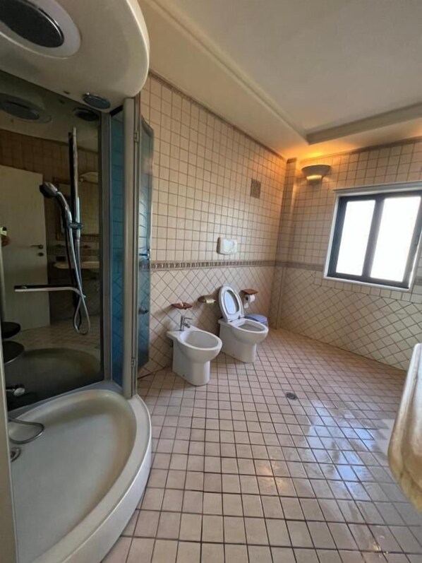 A bathroom with a shower, two toilets, and a bathtub. - Green Garden Villa (Durrës)