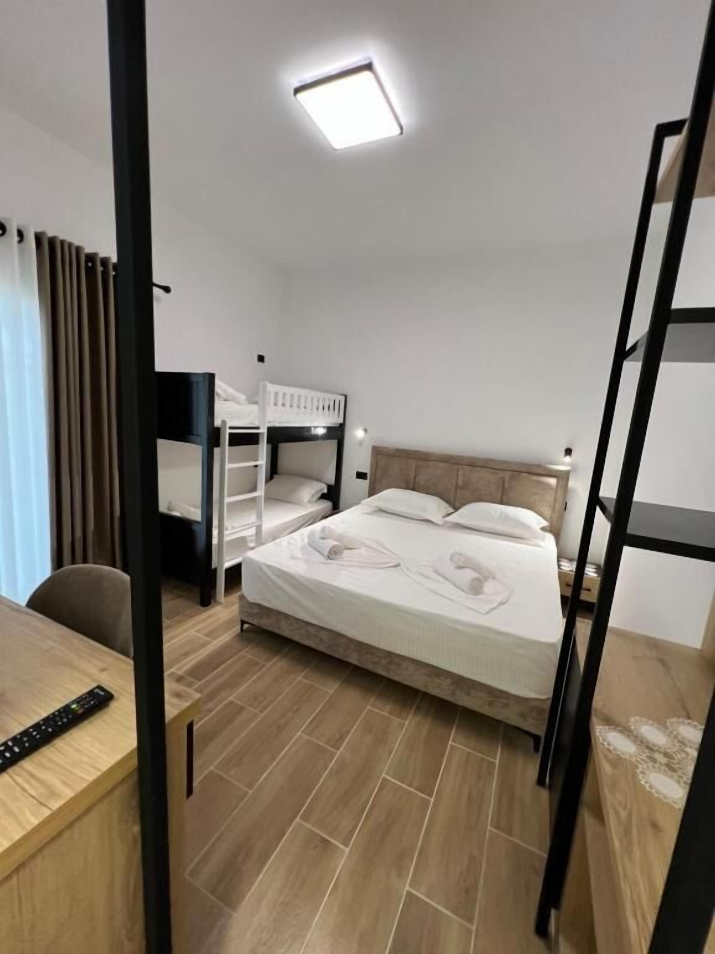 Une chambre d’hôtel avec un lit superposé, un bureau avec une télécommande et un luminaire au plafond.