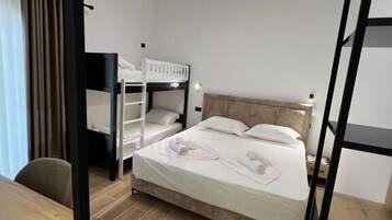 Une chambre d’hôtel avec un lit superposé, un bureau avec une télécommande et un luminaire au plafond.