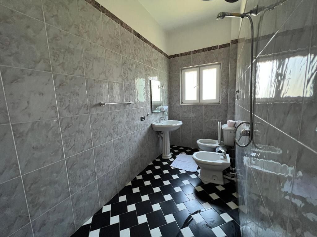 Une salle de bain avec un carrelage à motifs géométriques, un lavabo, un bidet et une douche.