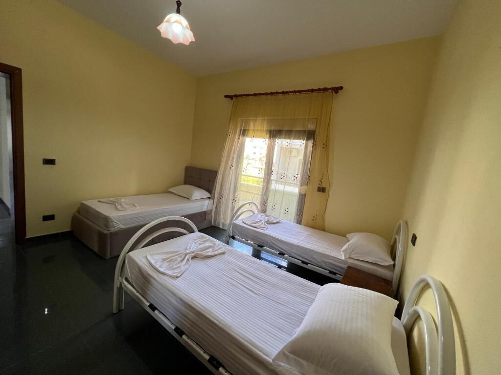A room with two single beds, a window with curtains, and a ceiling light.