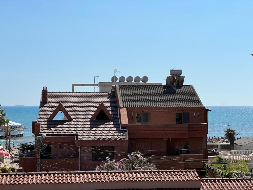 Un edificio de dos plantas con techo de tejas, un balcón y vista al mar.