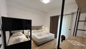 Une chambre avec deux lits, un bureau en bois et un luminaire au plafond.