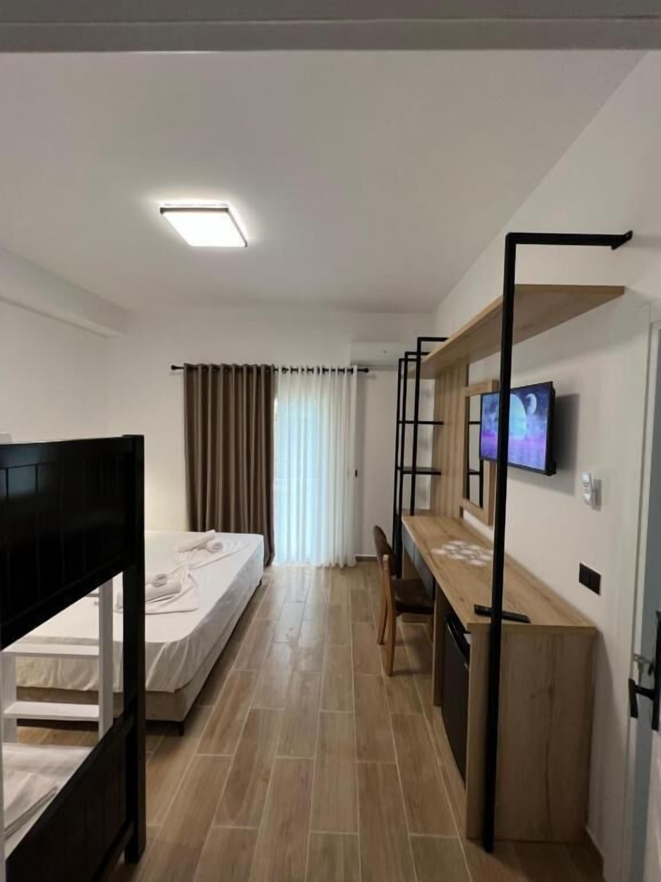A modern hotel room with a bunk bed, a desk with a computer, and a TV on the wall.