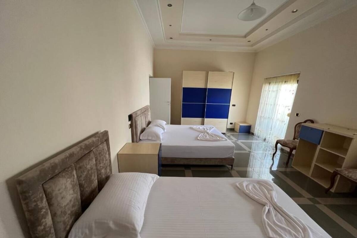 A hotel room with two beds, a wardrobe, a desk, and a chair.