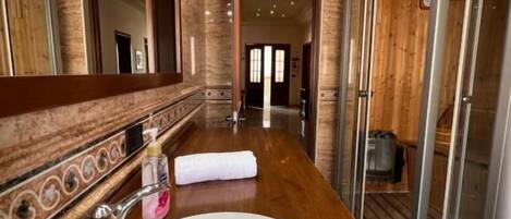 A bathroom with a large mirror, a white sink, and a wooden vanity.