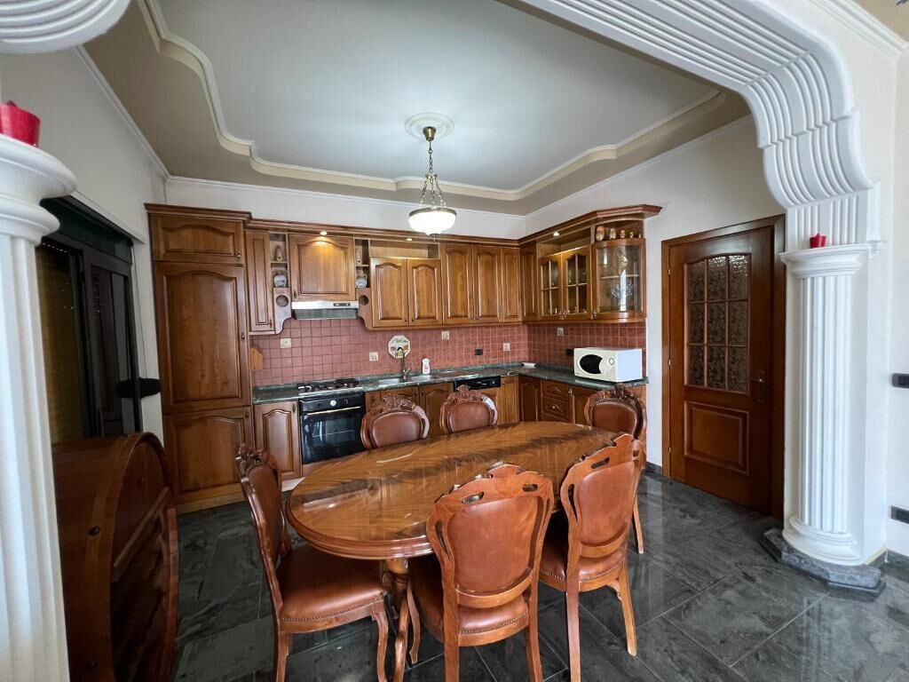 Una cocina amplia con una isla grande, armarios de madera y un comedor con mesa y sillas de madera.