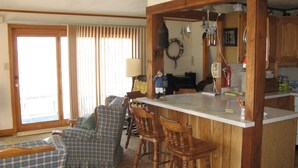 A cozy living room with a wooden bar area, a fireplace, and a dining area with bar stools.