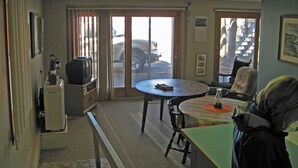 Una habitación con una mesa de comedor, sillas, un banco, un televisor y un radiador.
