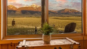Un interior de madera con un ventanal grande que da a un paisaje montañoso.