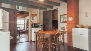 A kitchen with wooden cabinets, a dining table with chairs, a microwave, and a toaster.
