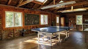 A ping pong table in a wooden cabin with large windows and a skylight.