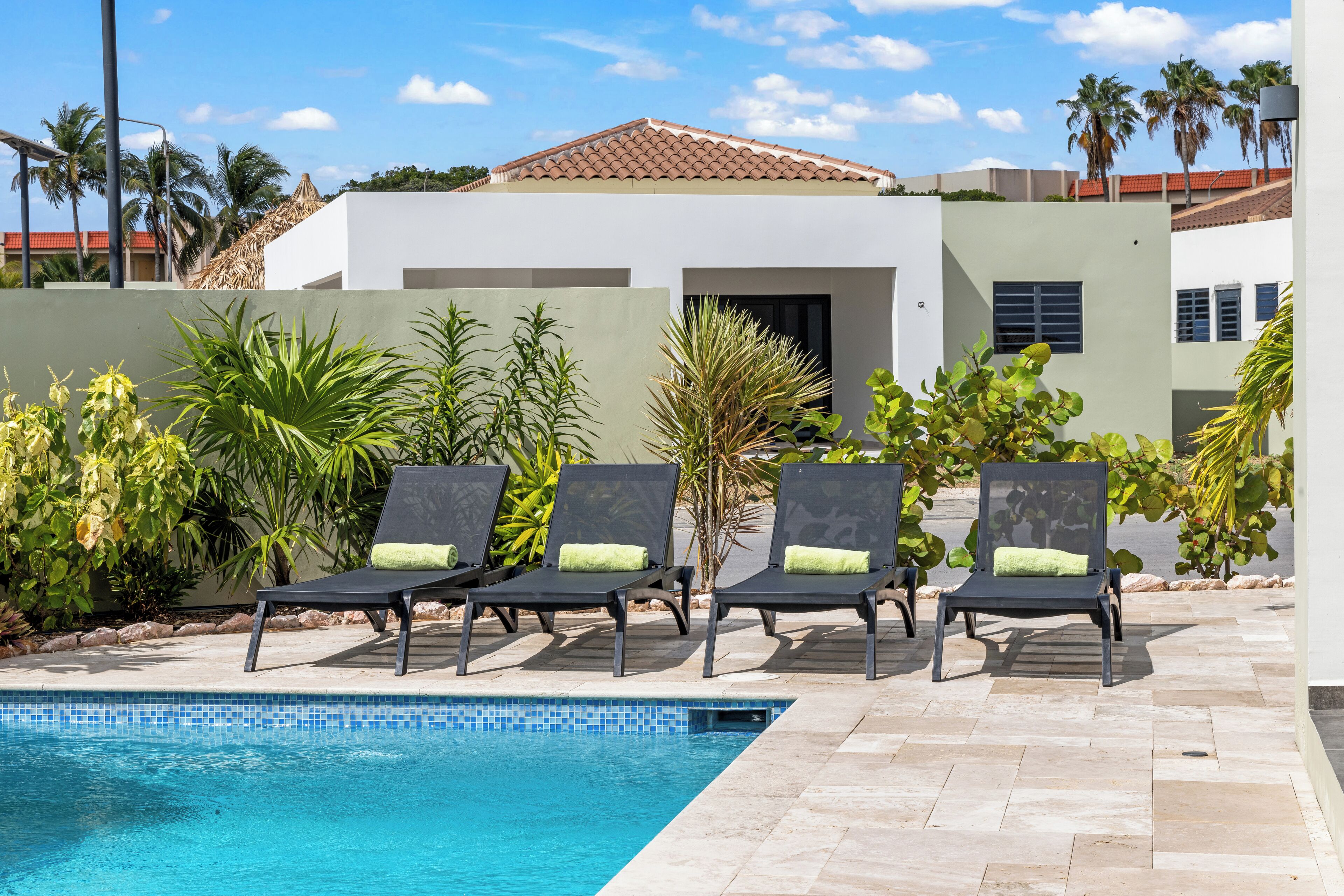 Zona junto a la piscina con sillones de descanso y una vista despejada del agua.
