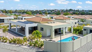 A residential area with modern houses, a swimming pool, and solar panels. - Villa Amber with pool at mambo beach (Willemstad)