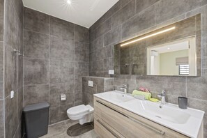 A modern bathroom with a large sink, mirror, and shower. - Villa Amber with pool at mambo beach (Willemstad)