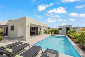 A modern pool area with lounge chairs and a clear blue sky. - Villa Amber with pool at mambo beach (Willemstad)